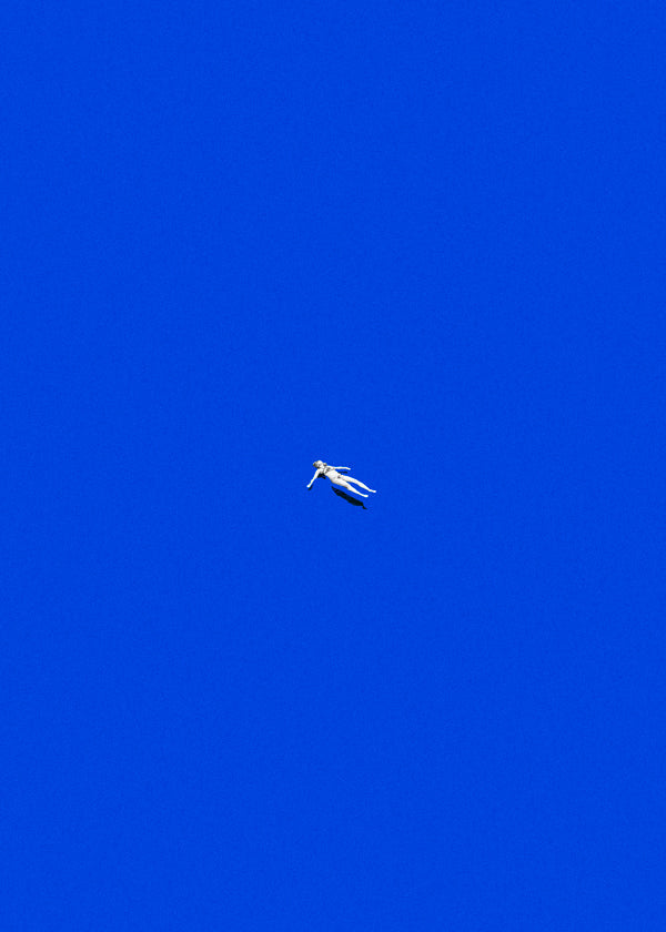 Minimalistisch kunstwerk met drijvend figuur tegen blauwe lucht