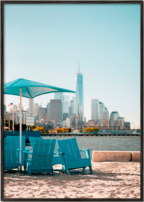 Reiseposter mit türkisfarbenen Strandstühlen und Stadtskyline – Black Frame